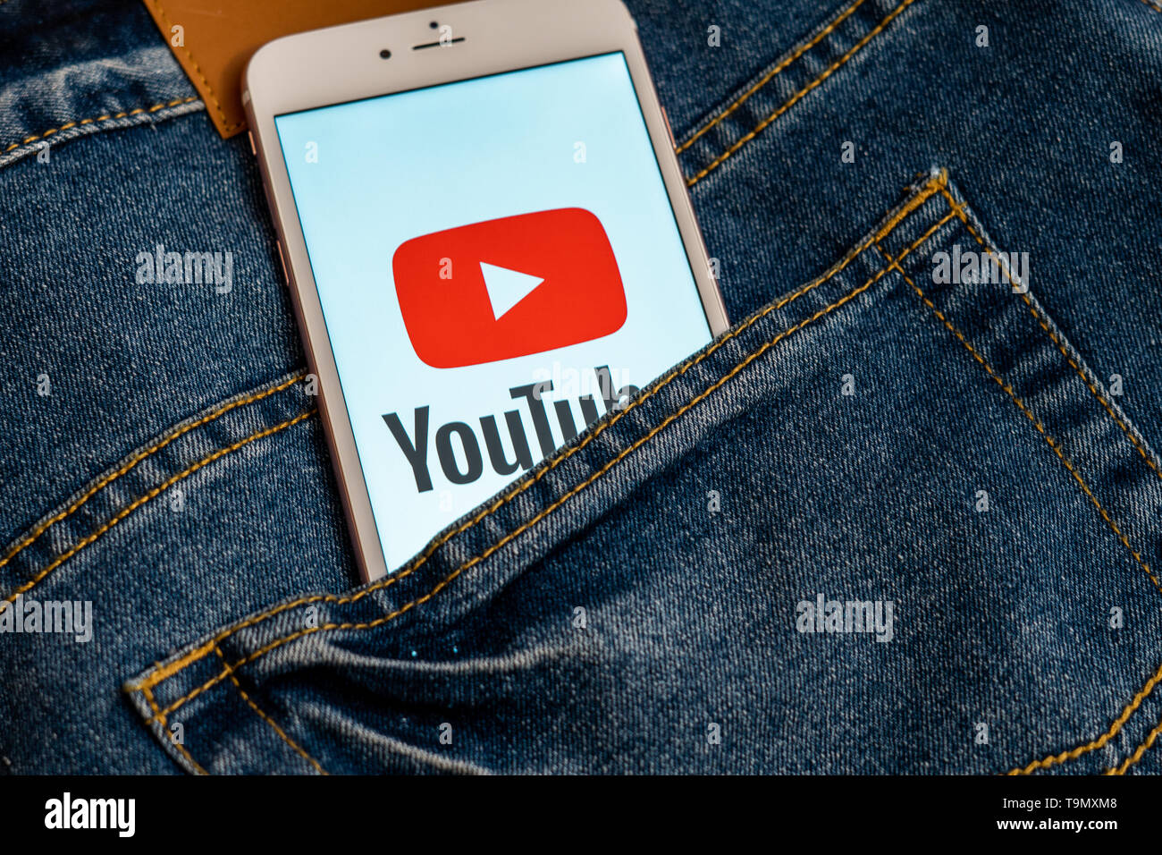 Weißes iPhone mit Logo von social media YouTube auf dem Bildschirm. Social media Symbol. Denim Jeans Hintergrund. Marketing oder Business Konzept. Stockfoto