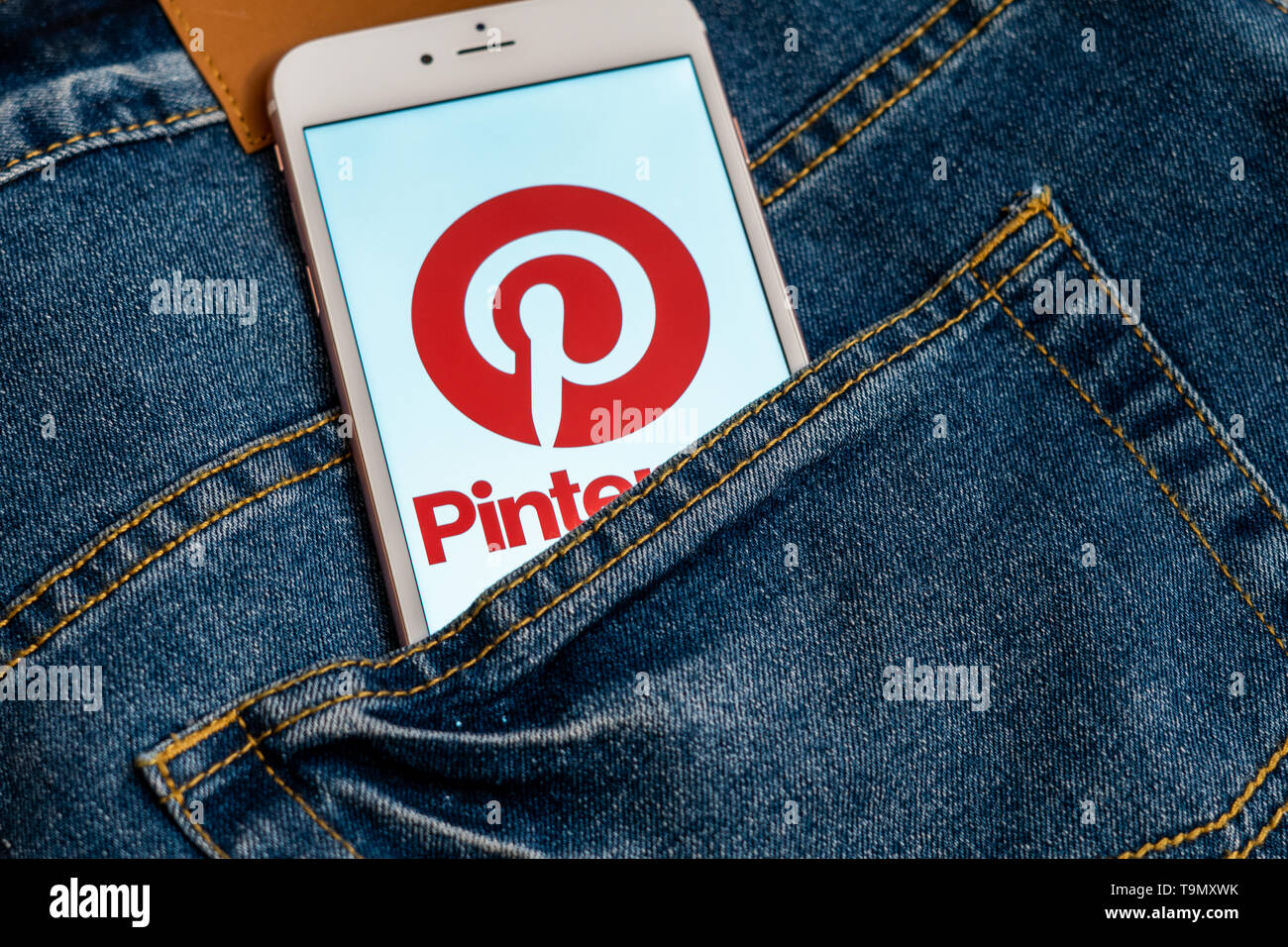 Weißes iPhone mit Logo von social media Pinterest auf dem Bildschirm. Social media Symbol. Denim Jeans Hintergrund. Marketing oder Business Konzept Stockfoto