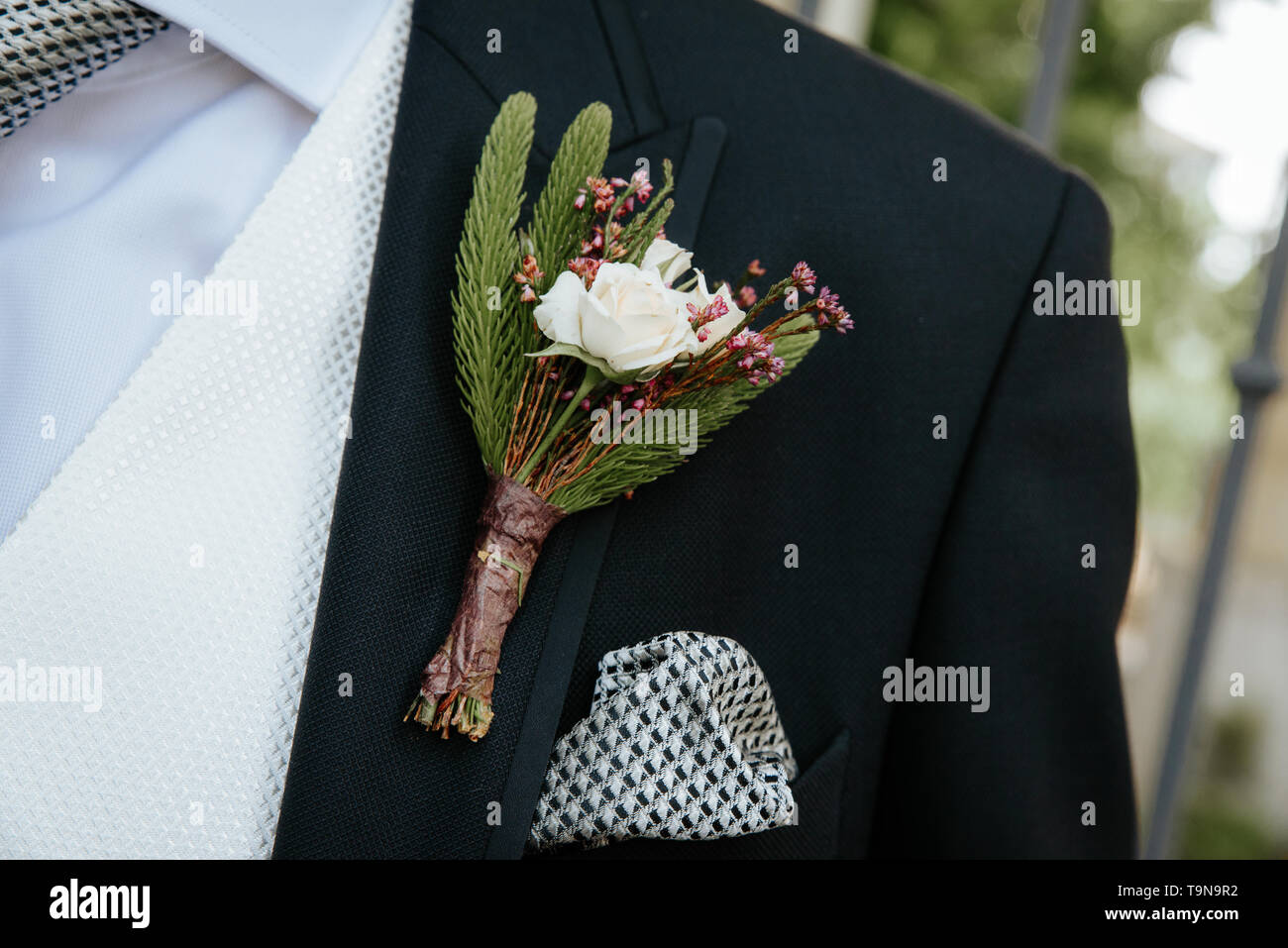 Anstecker mit einer Rose und Zweig Tanne auf dem Hintergrund der Jacke des Bräutigams. Stockfoto
