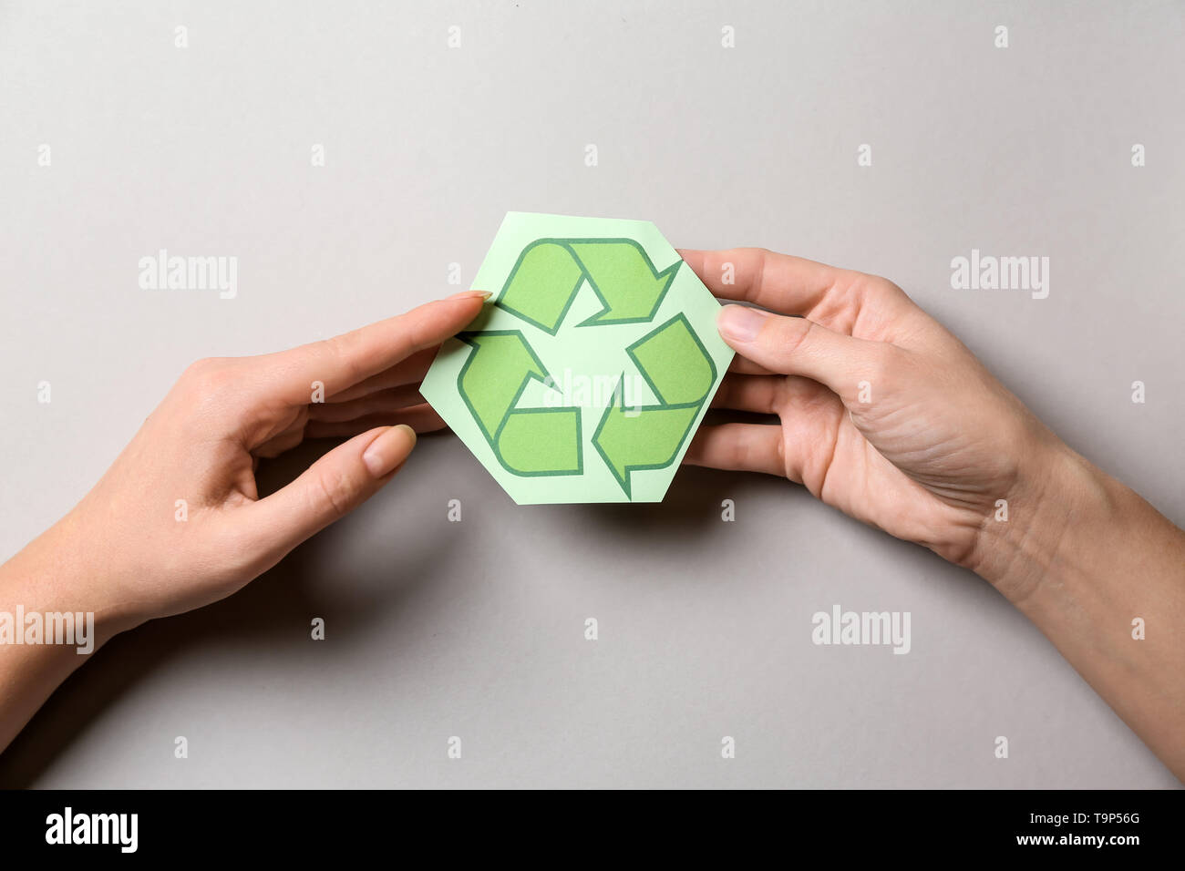 Weibliche Hände mit Recycling Symbol auf hellen Hintergrund Stockfoto