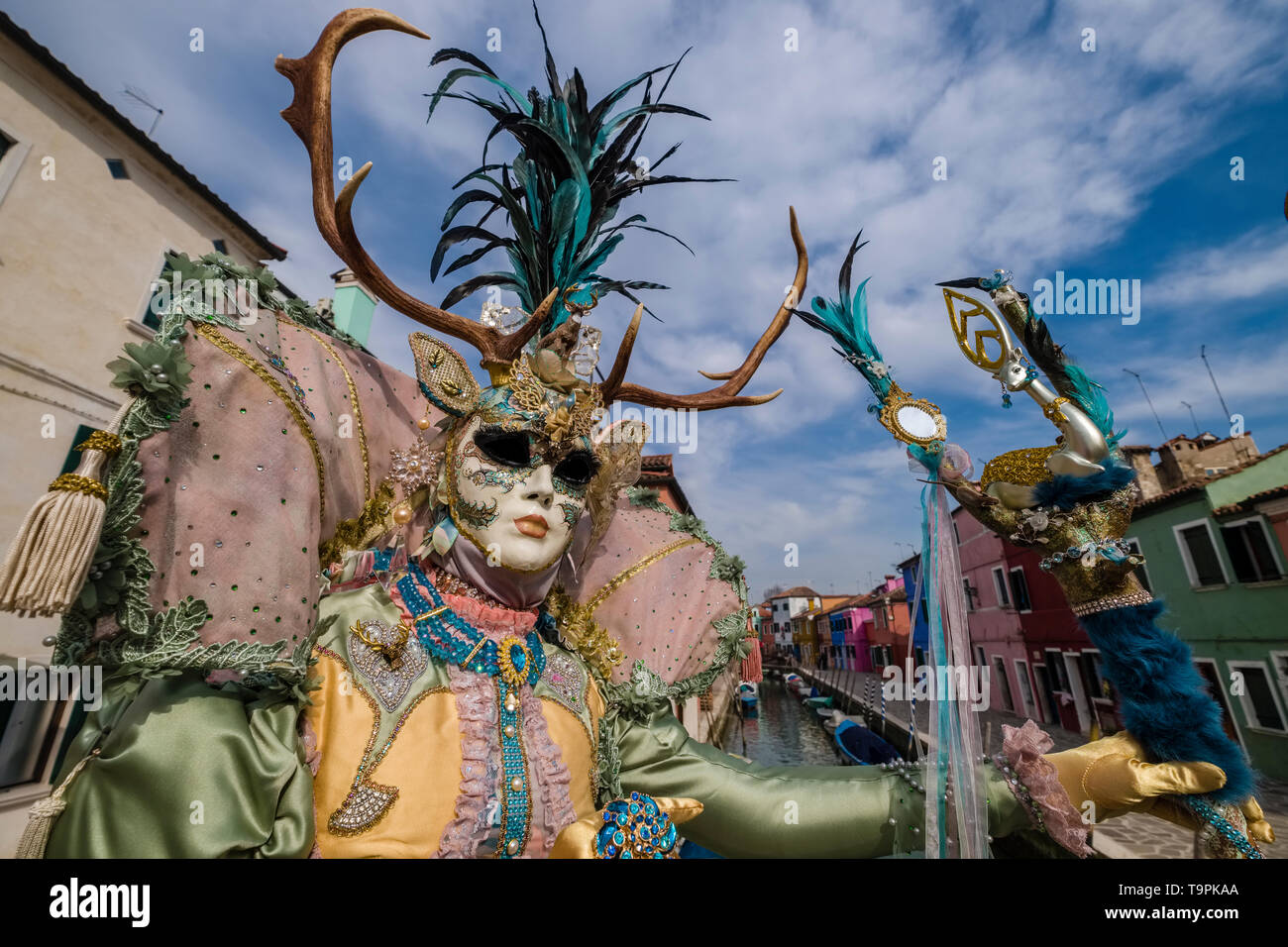 Eine feminine maskierte Person in einem schönen kreativen Kostüm, auf der Insel Burano posiert, feiert die Venezianischen Karneval Stockfoto