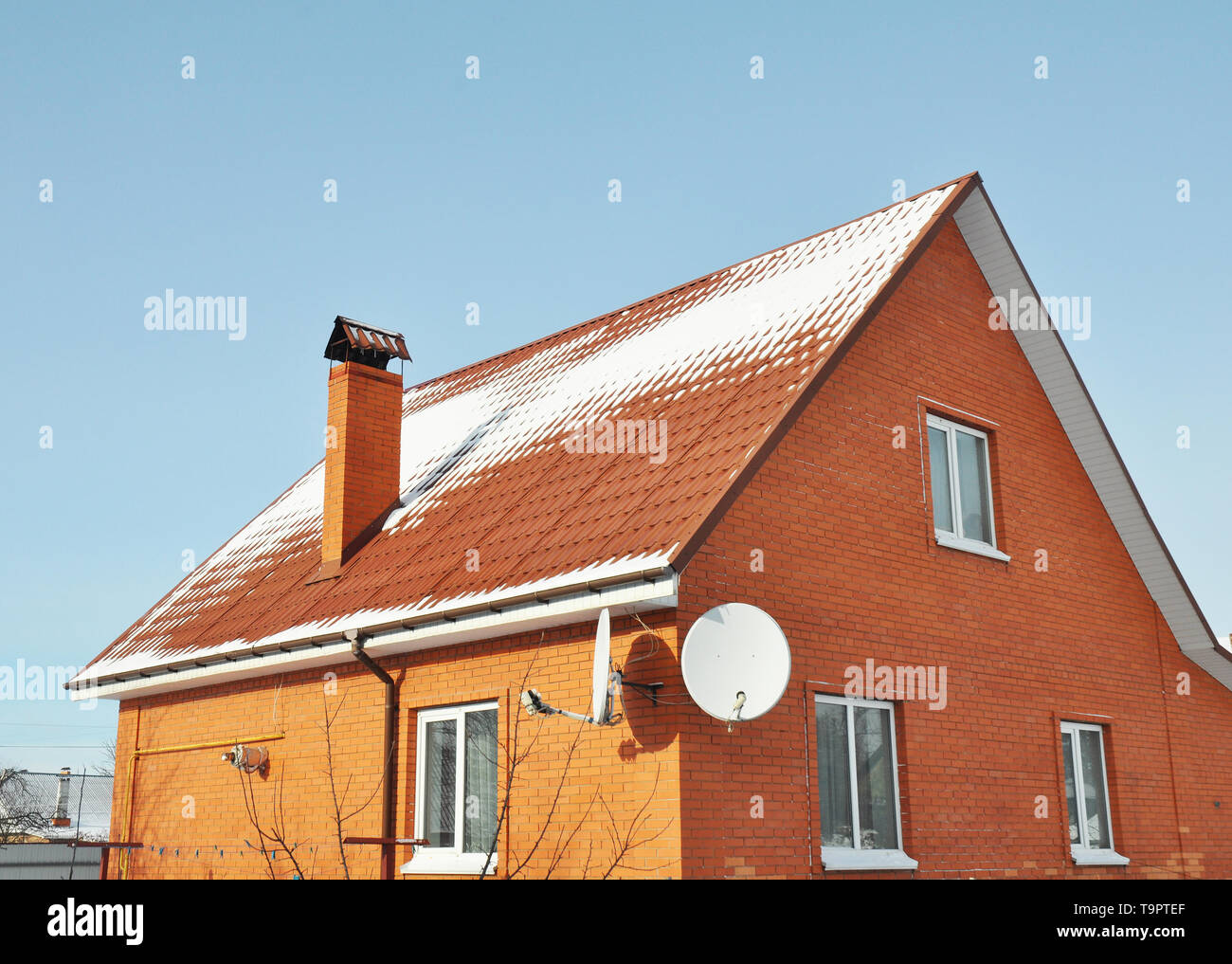 Rote metall Dachziegel und Schornstein mit Schnee bedeckt Stockfoto