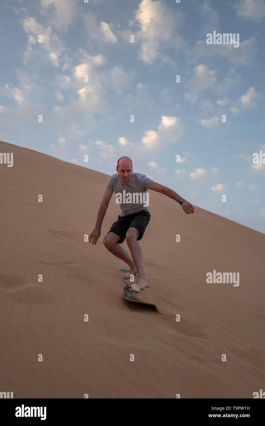 Touristen in Abu Dhabi versuchen Sandboarding in den Dünen der UAE Desert Stockfoto