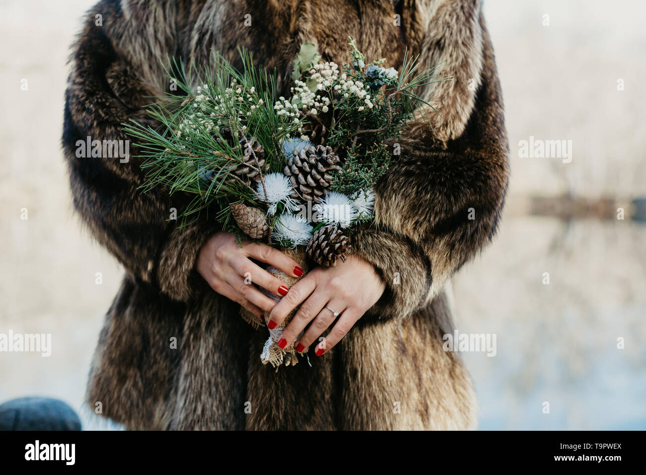 Eine Braut in einem pelzmantel Holding ein Winter Brautstrauß Stockfoto