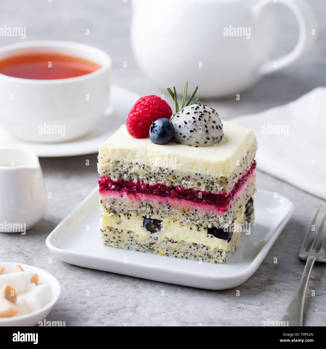 Berry, Mohn geschichteten Kuchen auf weiße Platte. Grauer Hintergrund. Close Up. Stockfoto