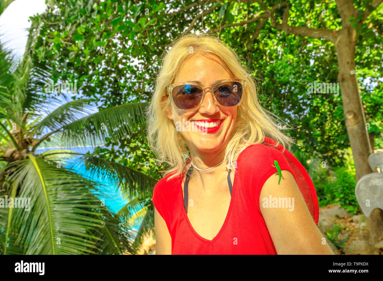 Ein niedliches Phelsuma sundbergi namens La Digue Taggecko auf dem Arm eines lächelnden touristische Frau auf Urlaub auf den Seychellen. Happy kaukasischen Frauen genießt mit Stockfoto