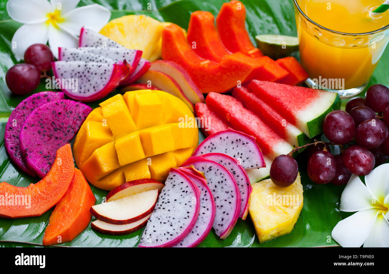 Tropische Früchte Sortiment mit frischen Saft, palm leaf Hintergrund. Ansicht von oben. Close Up. Stockfoto