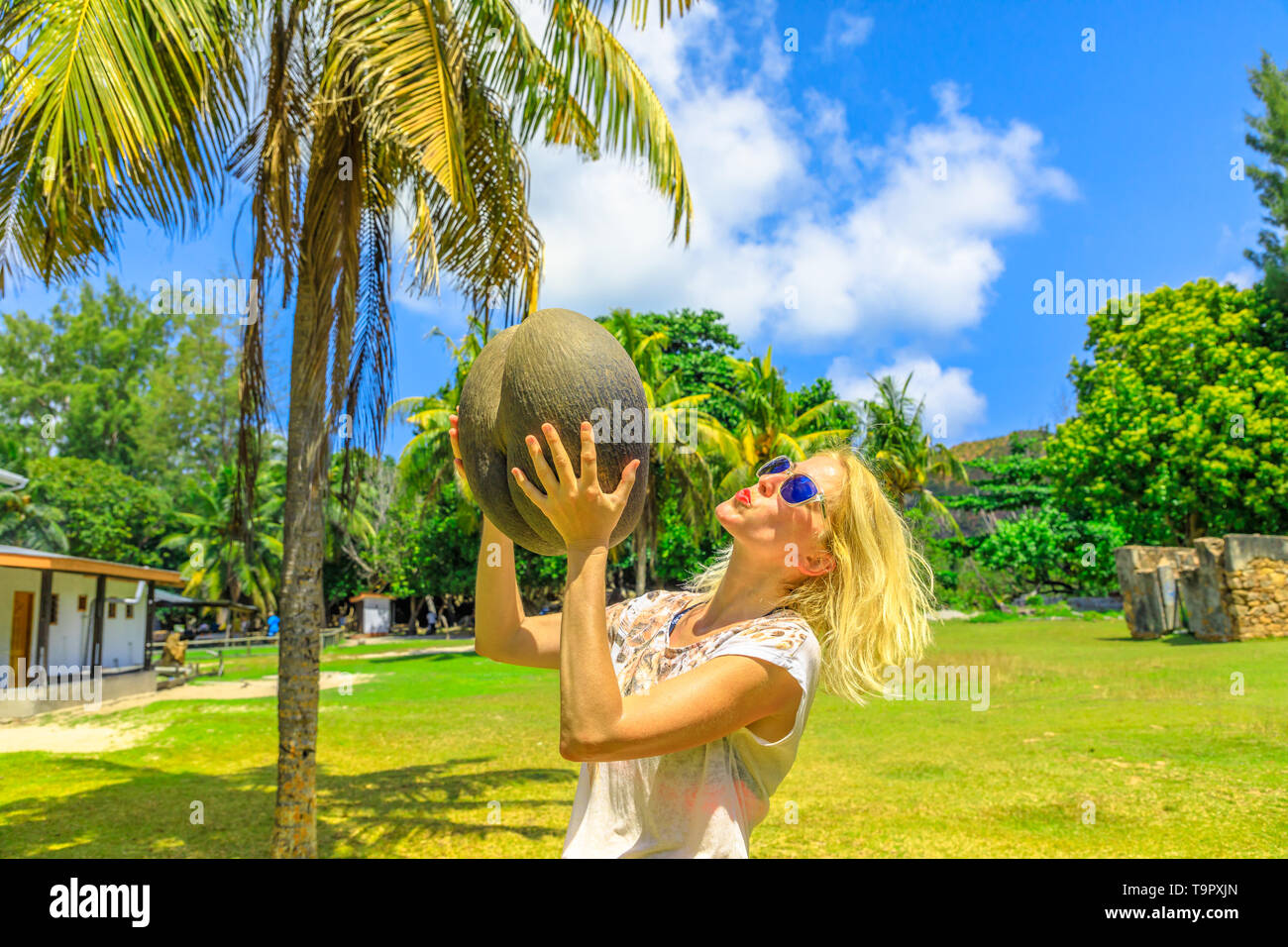 Touristische Frau mit Küssen und eine weibliche Lodoicea Maldivica Mutter wie Meer Kokosnuss auf Curieuse, inneren Inseln, Seychellen bekannt. Die Coco de Mer ist Stockfoto