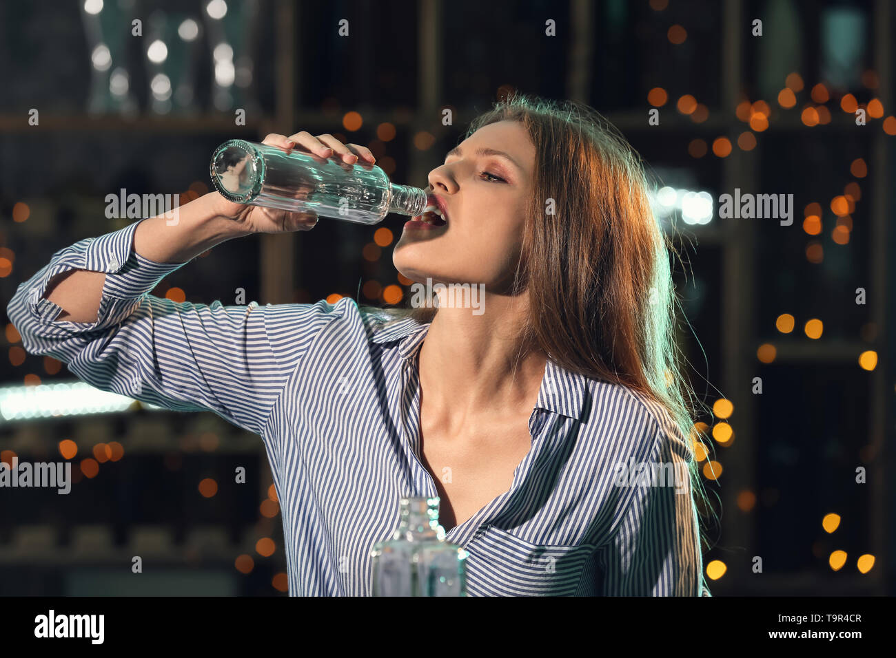 Junge Frau trinkt Alkohol in bar Stockfoto