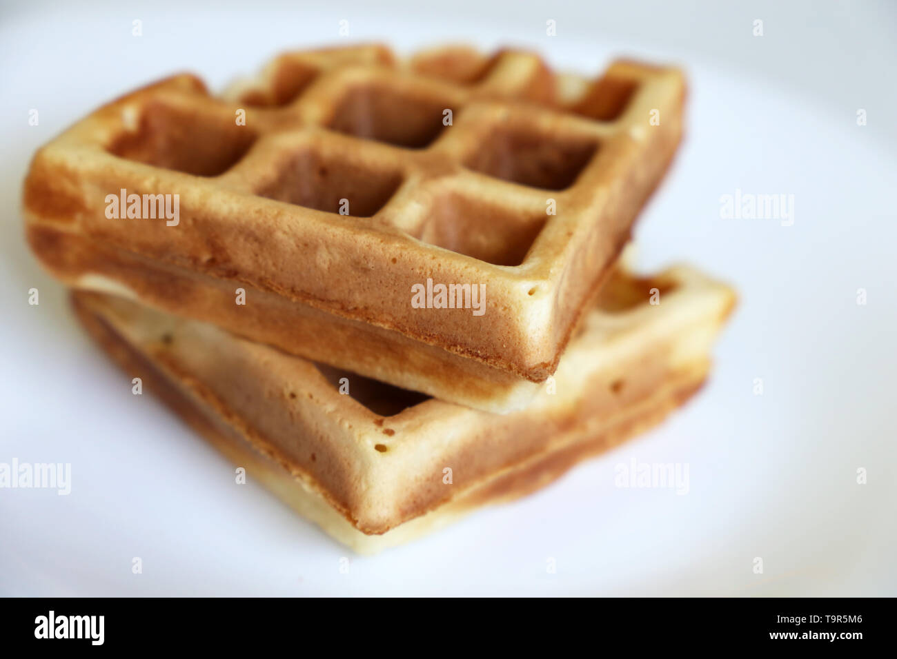 Belgische Waffeln in einer weißen Platte. Gesundes Frühstück, Stücke von frisch gebackenem classic Wafer, Kalorien essen Stockfoto