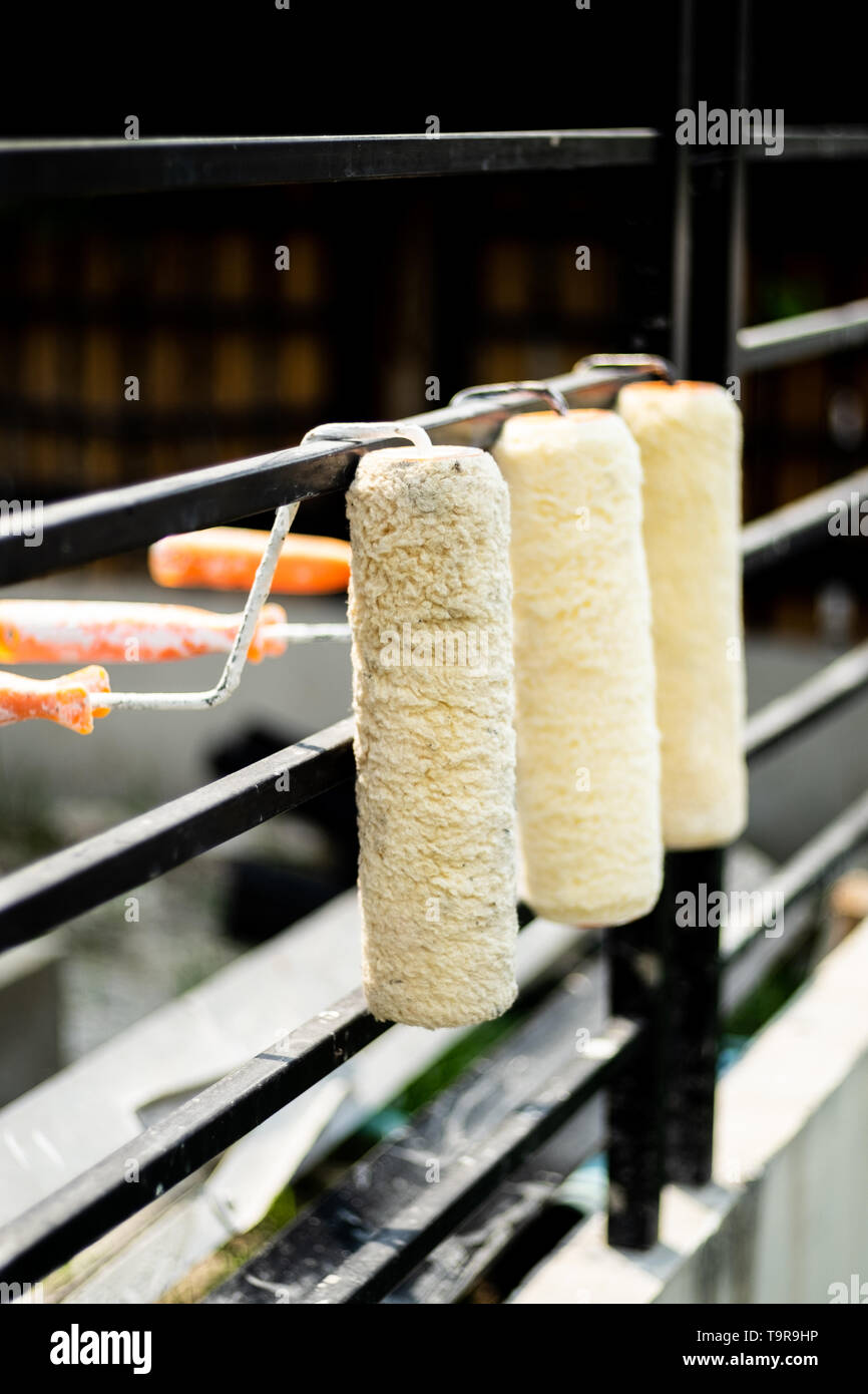 Reihe von farbroller Abdeckung auf eine schwarze Schiene aufgehängt, nach der Benutzung und Reinigung für den nächsten Einsatz warten, selektiven Fokus. Stockfoto