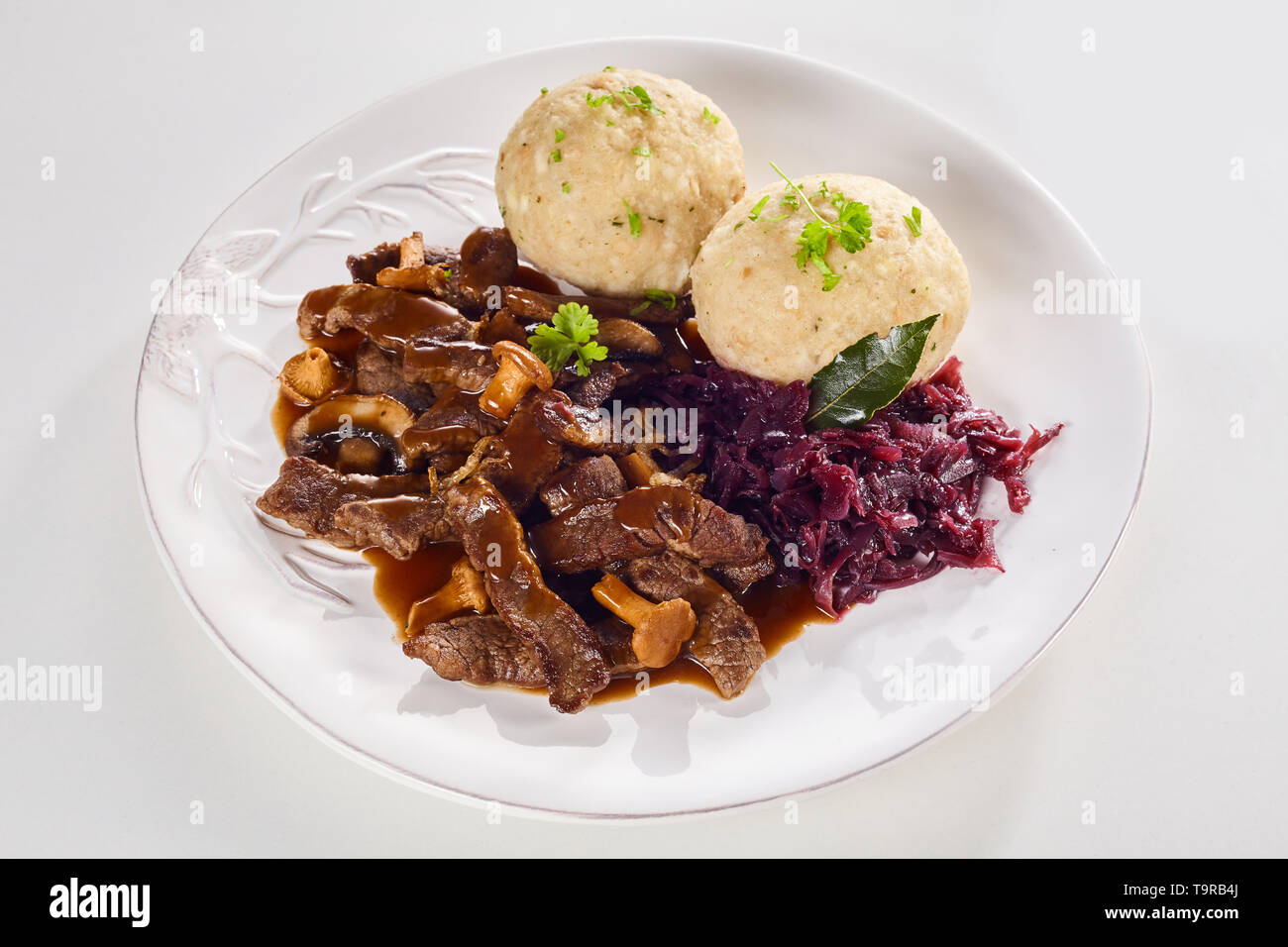 Platte der köstliche Schweizer Ragout mit Streifen von Fleisch in einer  reichen Sauce mit Champignons mit Rotkohl und Knödeln garniert mit Kräutern  serviert Stockfotografie - Alamy