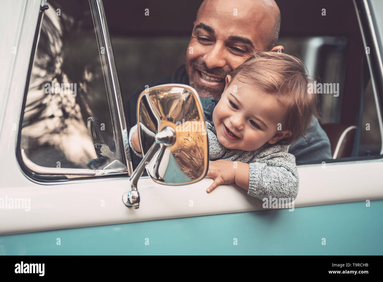 Porträt einer fröhlichen Vater mit niedlichen kleinen Sohn, der ein Auto fährt, Papa Lehre sein kostbares Baby einen Van zu fahren, mit Freude die Zeit togethe Stockfoto