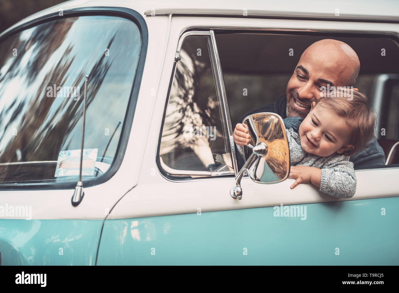 Kleiner Junge mit Vater Spaß im Auto, Papa und Sohn auf dem Fahrersitz sitzen im Van, Spielen und Blick in den Rückspiegel, glückliche fam Stockfoto