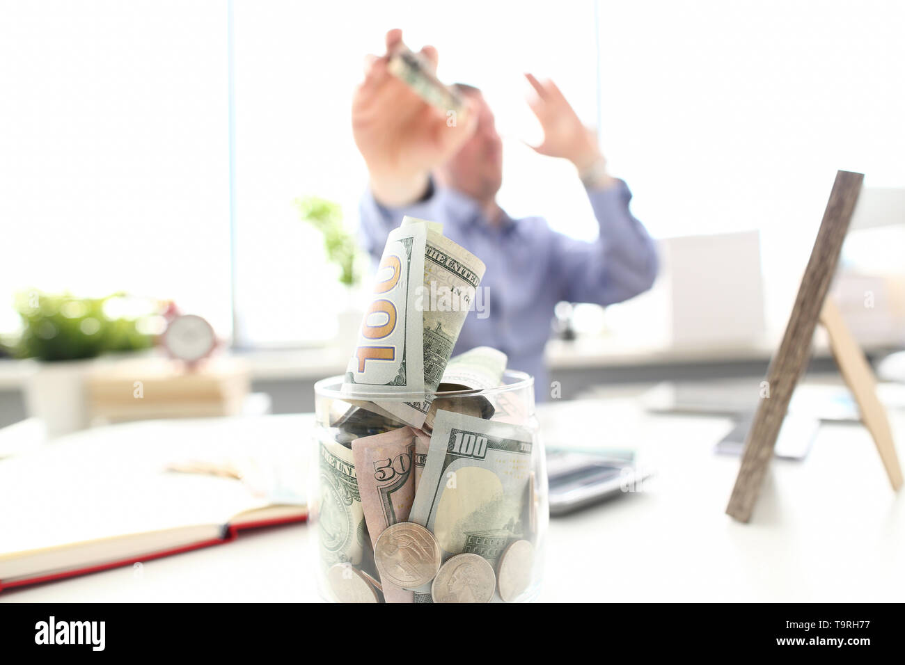 Reicher Mann uns werfen Banknoten in den großen Topf voller Geld am Arbeitsplatz Stockfoto