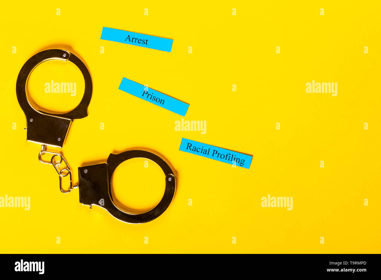Kriminalität Konzept Handschellen zeigt auf einem gelben Hintergrund mit Rasse Profiling Stockfoto