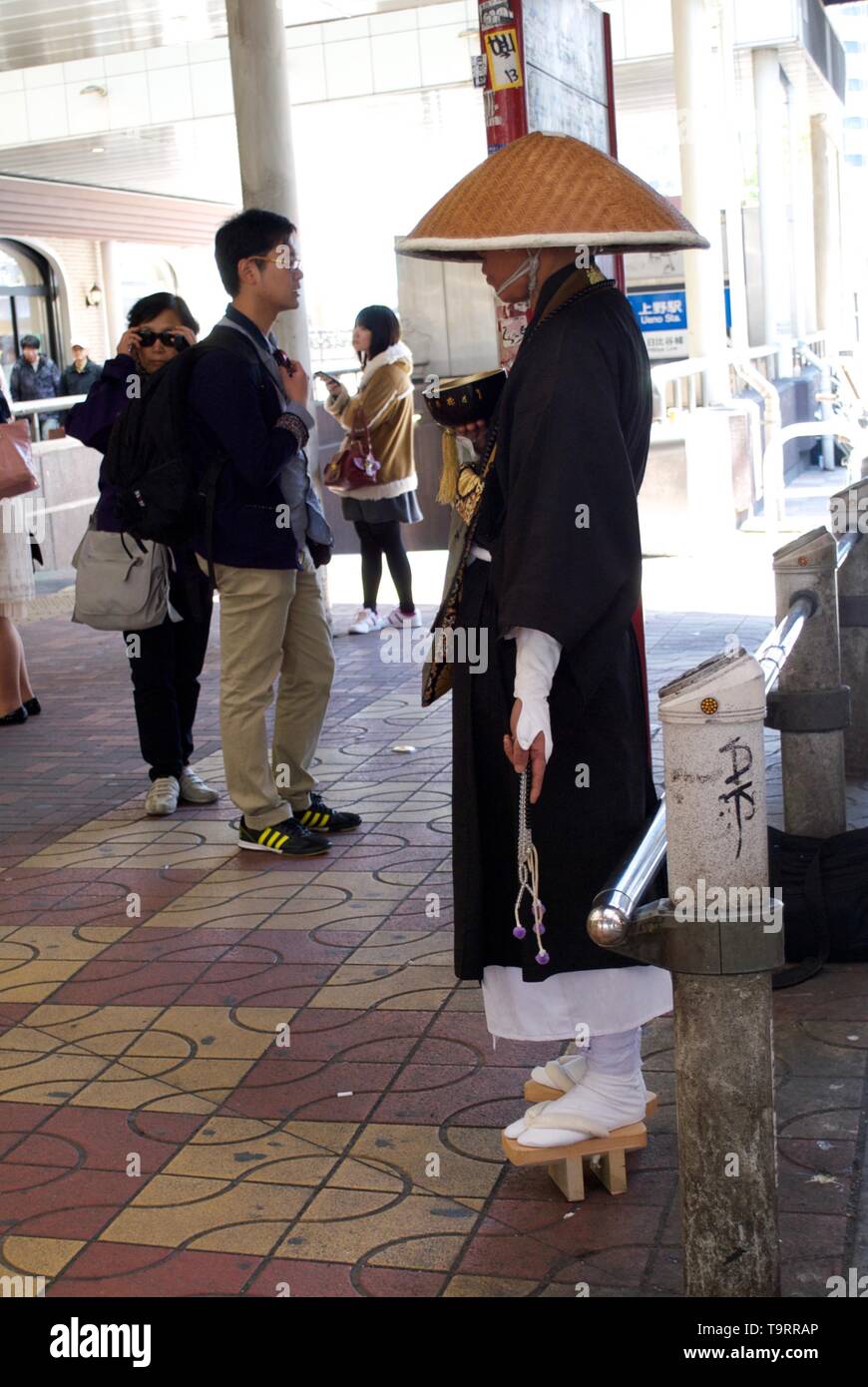 Ein Mönch warten geduldig auf Beiträge auf einer Tokyo street Stockfoto