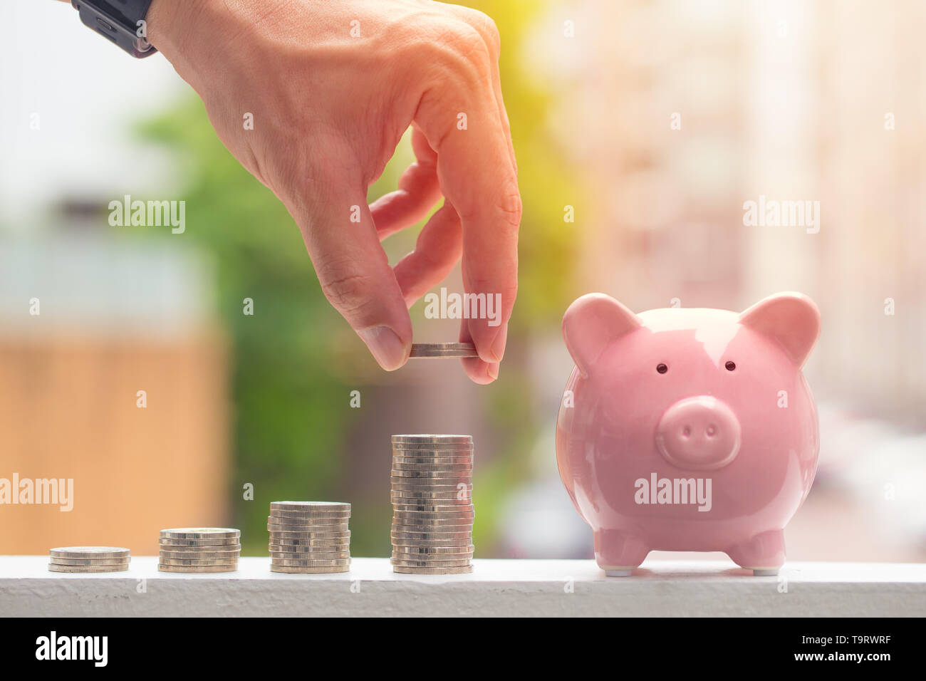Sparschwein mit Stapel von Münzen, männliche Hand Geld sparen Konzept Stockfoto