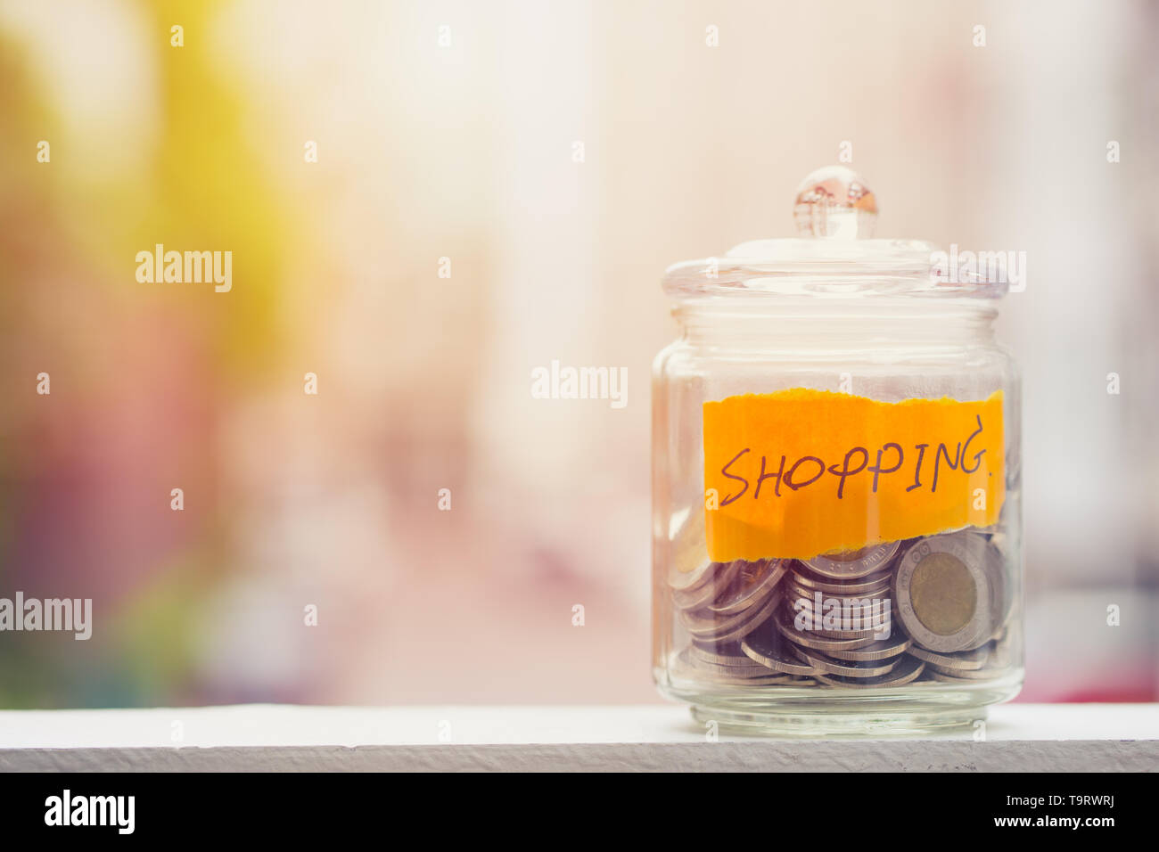 Geld sparen für Shopping Haushalt, Münzen in Glasflasche mit unscharfen Hintergrund Platz für Text Stockfoto
