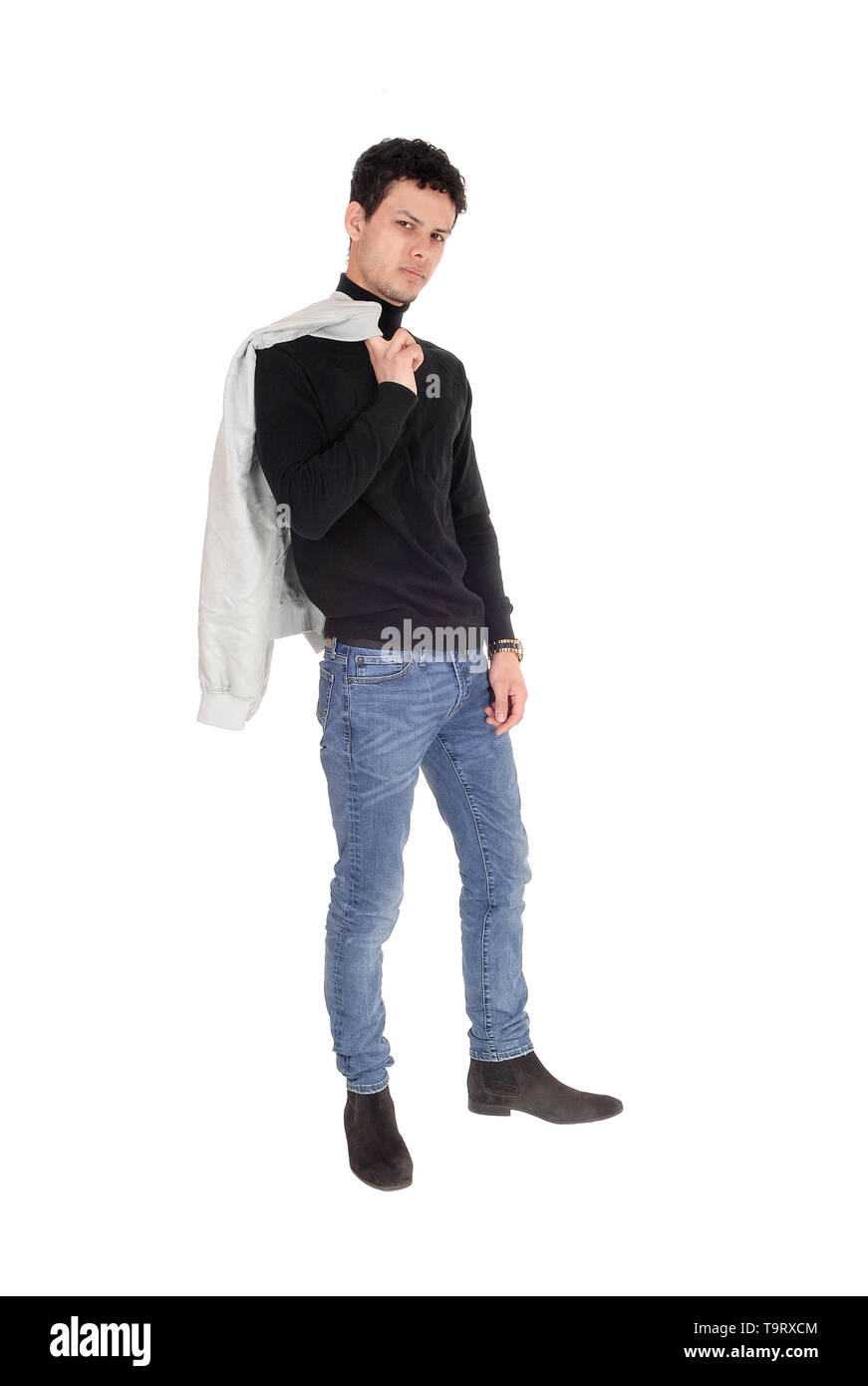 Ein gut aussehender junger Mann in einem schwarzen Pulli und Jeans mit seine Jacke über die Schulter, auf weißem Hintergrund Stockfoto