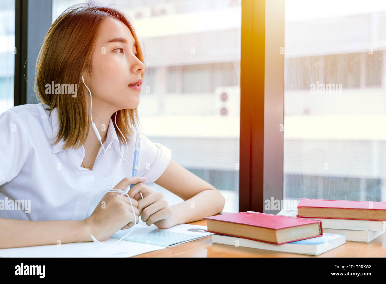 Nette junge Teen asiatische Universität Mädchen in Uniform lesen Buch in der Bibliothek Stockfoto