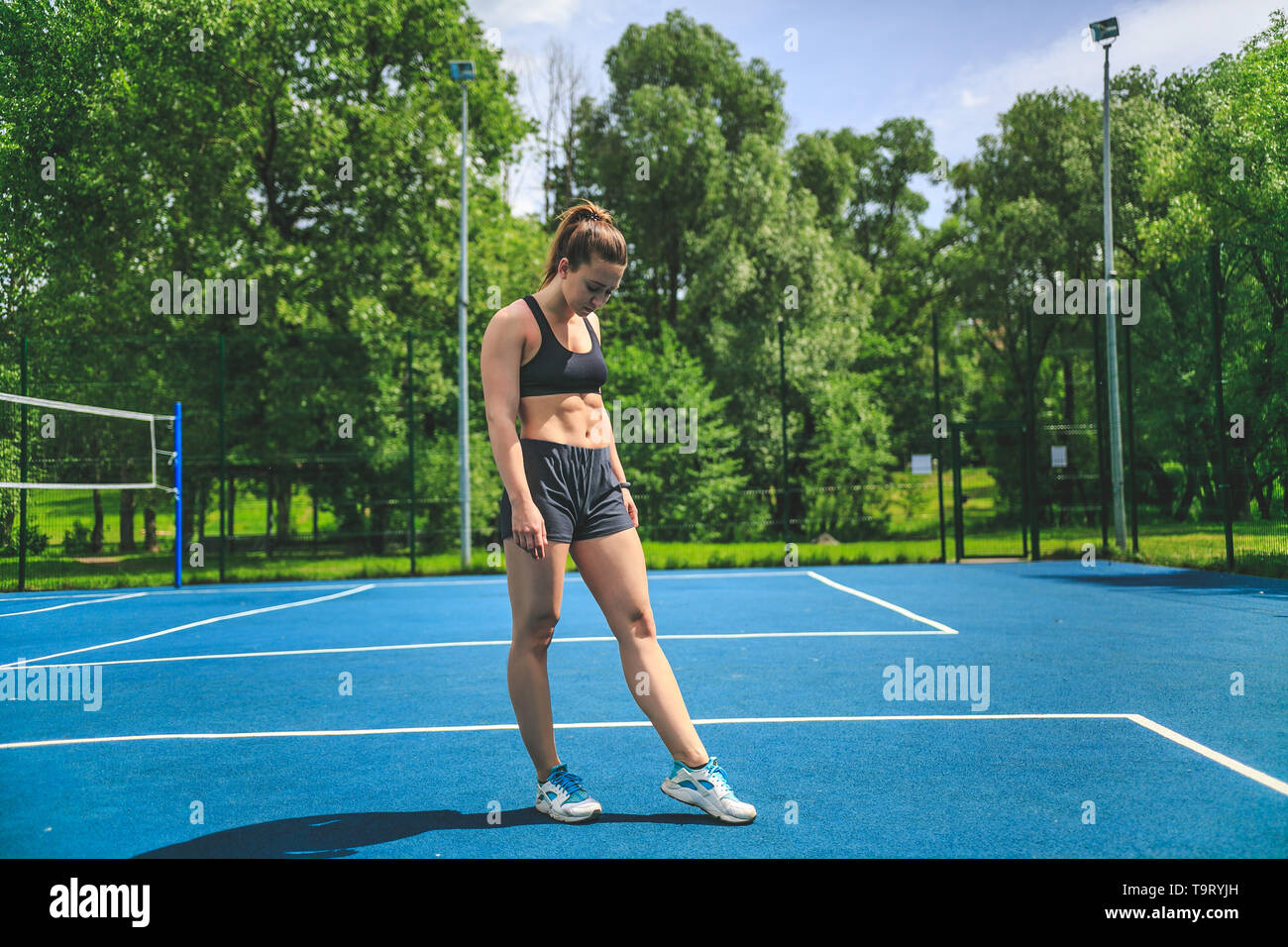 Sportliche Frau auf dem ABS-Suchen auf dem blauen Tennisplatz in Moskau Yauza Park. Stockfoto