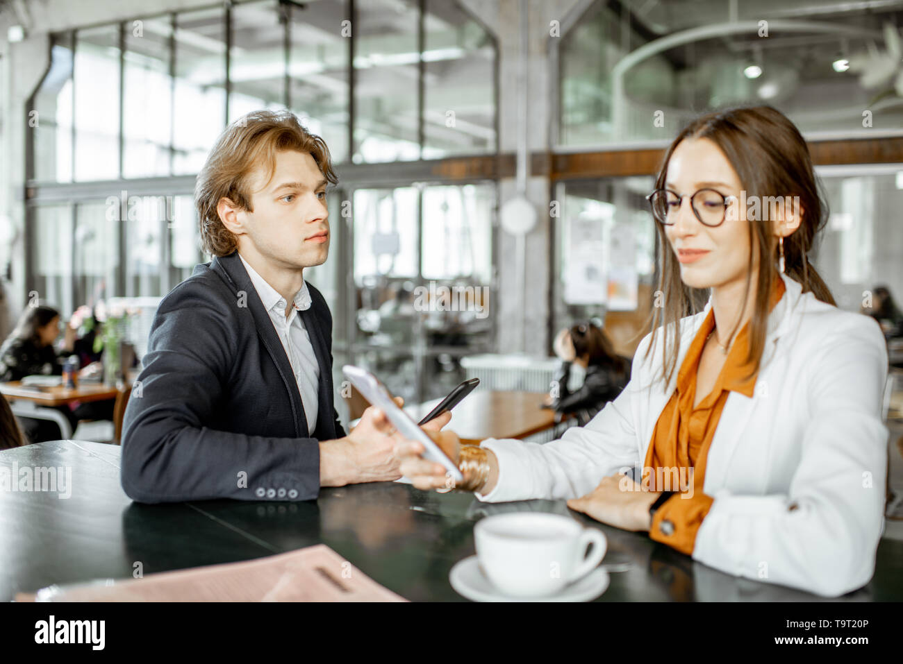 Junger Mann und Frau in business Gespräch beim Sitzen gemeinsam an der Bar oder im Coworking Space Stockfoto