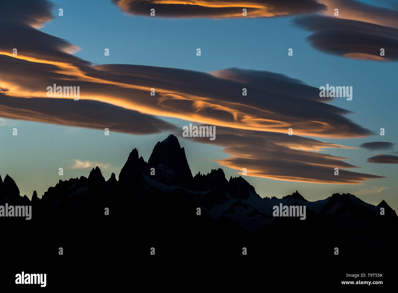 Bunte Linsenförmige Wolken über den Fitz Roy und Cerro Torre in Silhouette bei Sonnenuntergang im Nationalpark Los Glaciares in der Nähe von El Chalten, Argentinien. Stockfoto