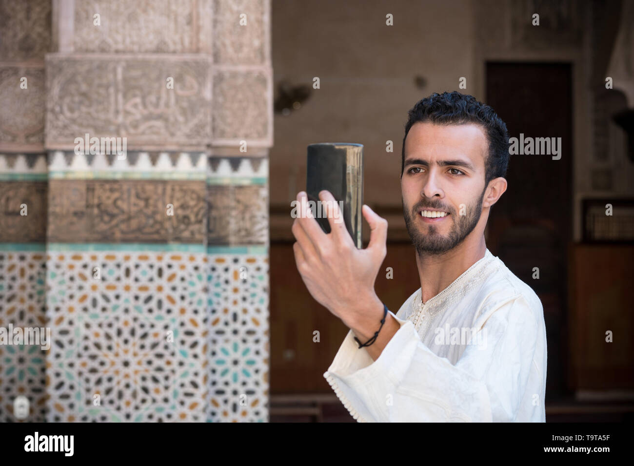 Junge muslimische Mann in traditioneller Kleidung lächelnd und unter selfie mit Handy Stockfoto