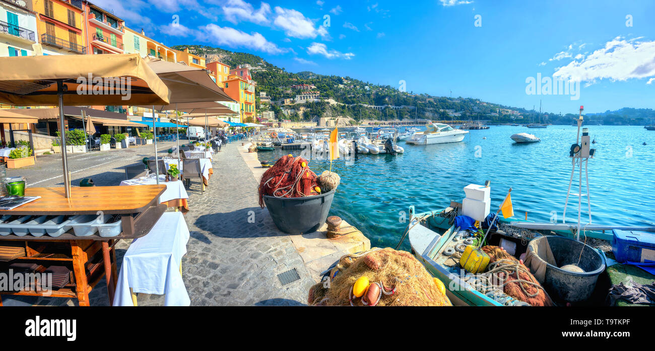 Panoramablick auf die Stadt mit Straßencafés und Fischerboot in Villefranche-sur-Mer. Cote d'Azur, Frankreich Stockfoto