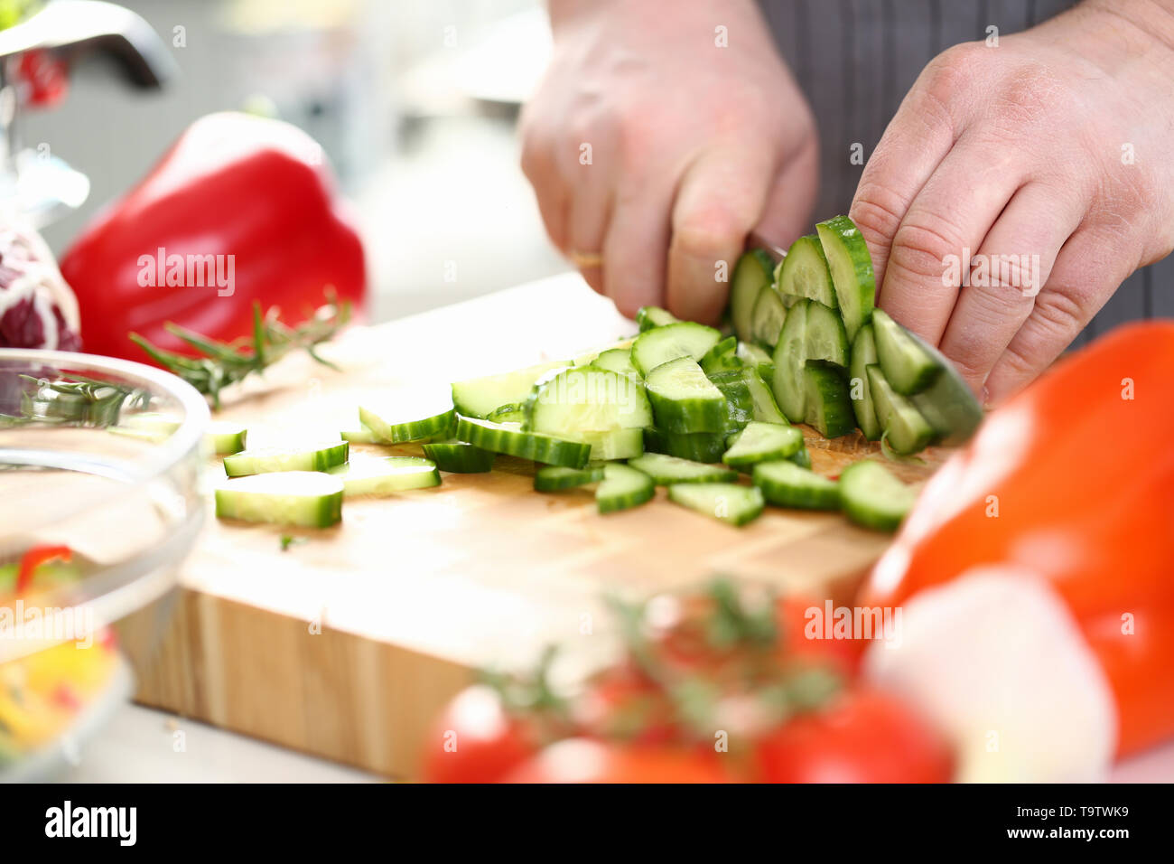Männliche Hände frische Gurke kleine Stücke hacken Stockfoto