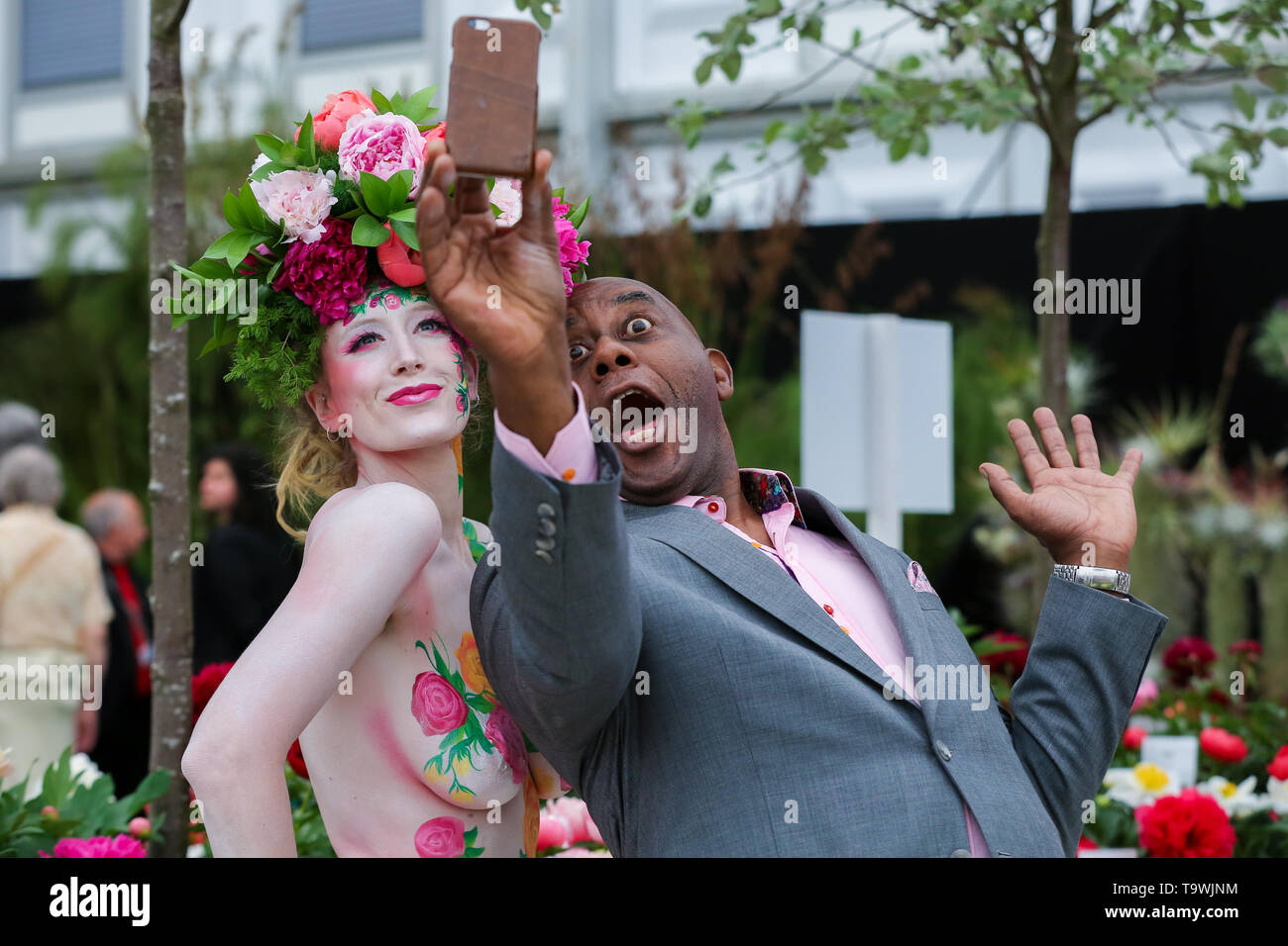 Mai 20, 2019 - London, Vereinigtes Königreich - Ainsley Harriott gesehen eine selfie mit einem Modell trägt ein Blumenarrangement hut mit Body Art während der Chelsea Flower Show.. der Königlichen Gartenbaugesellschaft Chelsea Flower Show ist eine jährliche Gartenschau über fünf Tagen auf dem Gelände des Royal Hospital Chelsea in London. Die Show ist für das Publikum geöffnet von 21. Mai bis 25. Mai 2019. (Bild: © Dinendra Haria/SOPA Bilder über ZUMA Draht) Stockfoto