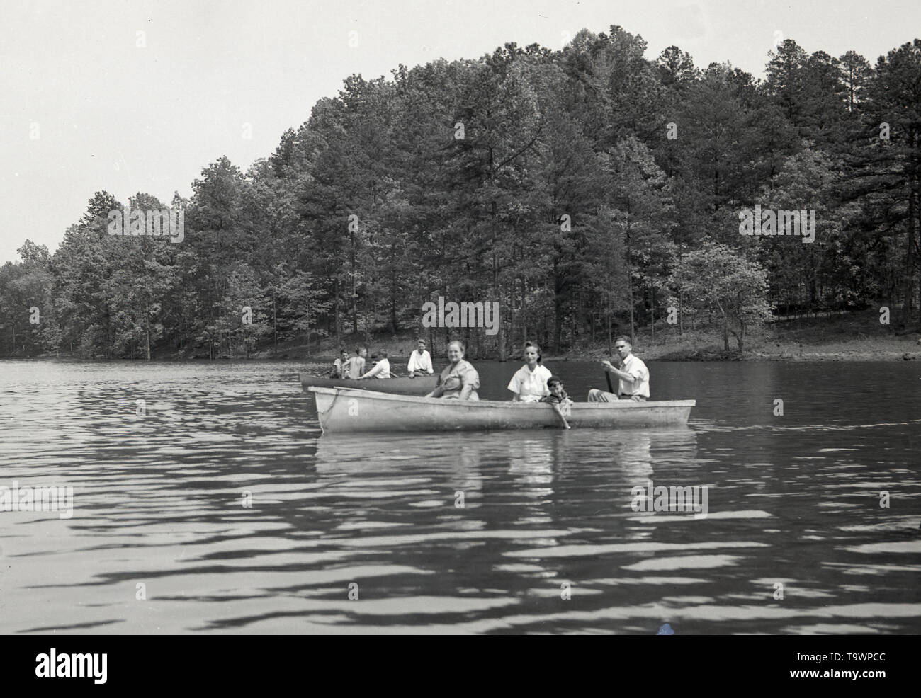 1950, historische, amerikanischen Familie in einem Paddelboot auf einem breiten Fluss in einem Waldgebiet, USA. Stockfoto