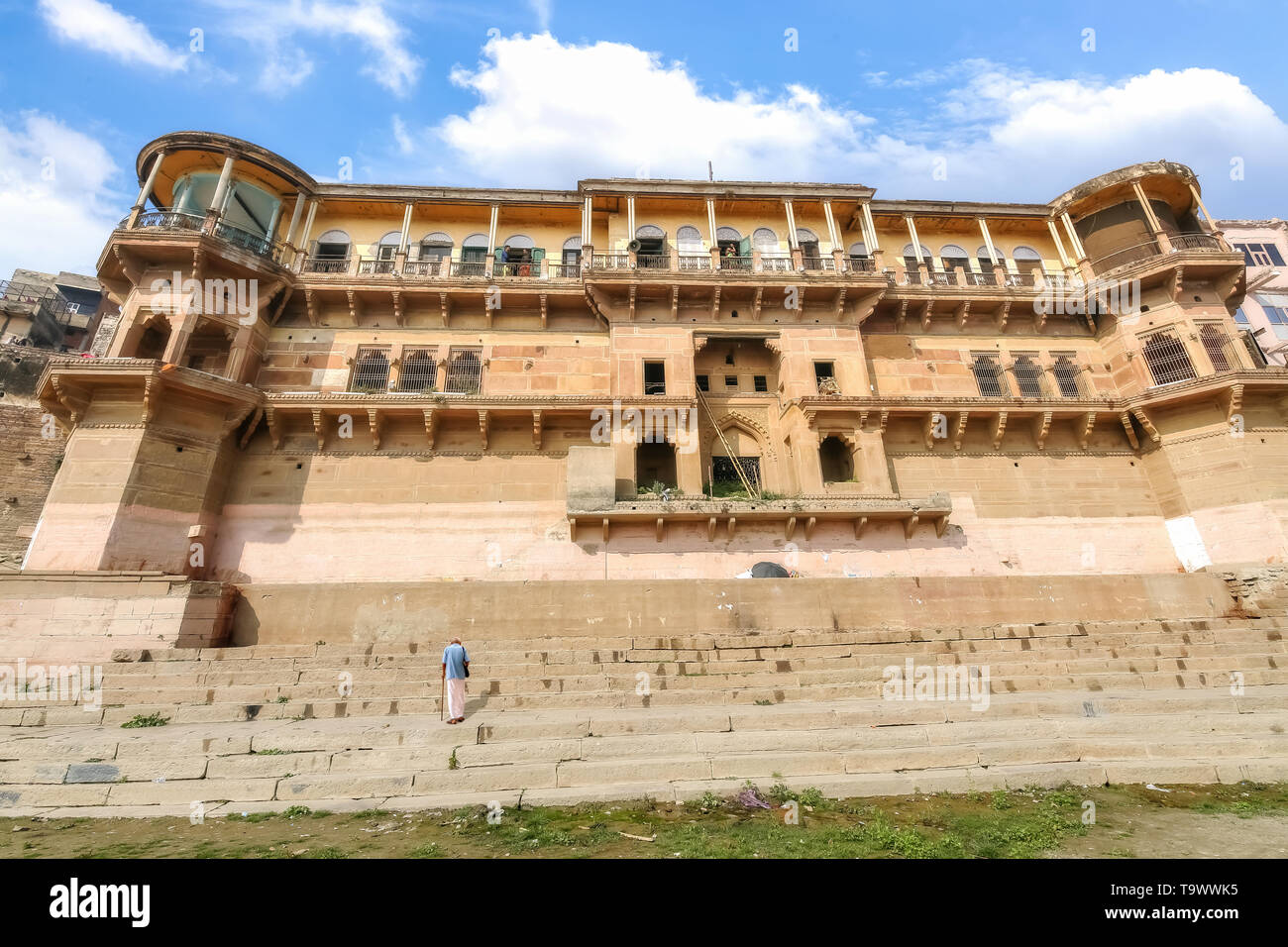 Vorderansicht eines alten denkmalgeschützten Gebäude in Varanasi Ganges ghat mit einem alten Mann gesehen klettern die Treppe Stockfoto