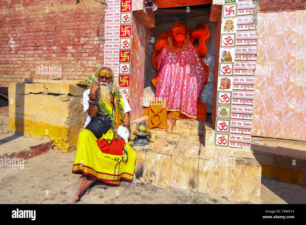Indischen Sadhu baba vor einem Hanuman Tempel in Varanasi Ganges ghat Sitzen Stockfoto