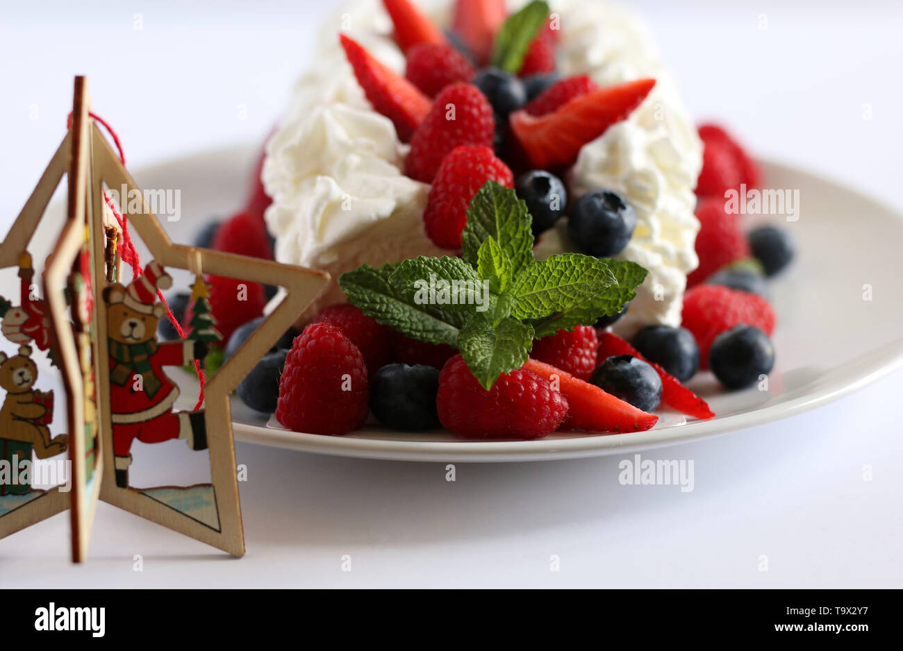 Ice Cream Cake mit Beeren auf weißem Hintergrund mit Weihnachtsschmuck. Stockfoto
