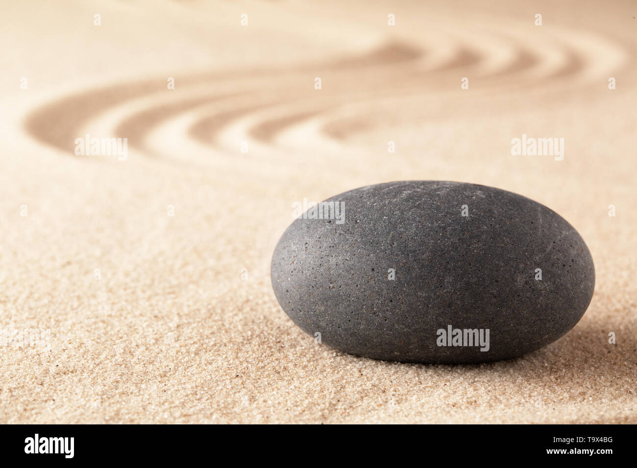 Spirituelle Stone Therapie, schwarzem Basalt round Rock auf sandigem Untergrund. Spa Wellness Behandlung. Stockfoto