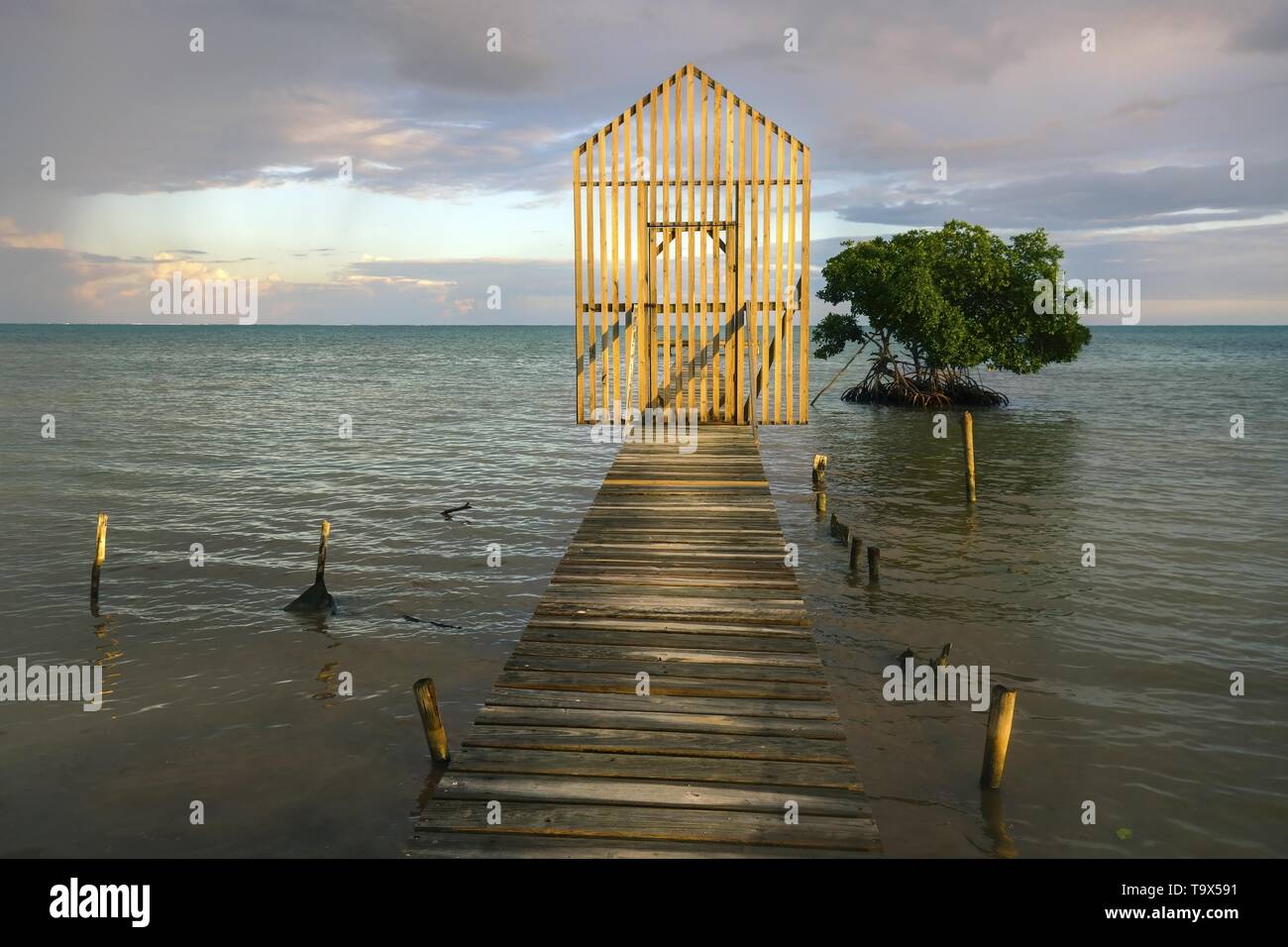 Sonnenuntergang Himmel Panoramablick auf die Landschaft von isolierten hölzerne Tor über die Fischerei Dock Pier mit fernen Karibischen Meer am Horizont auf Caye Caulker Insel, Belize Stockfoto