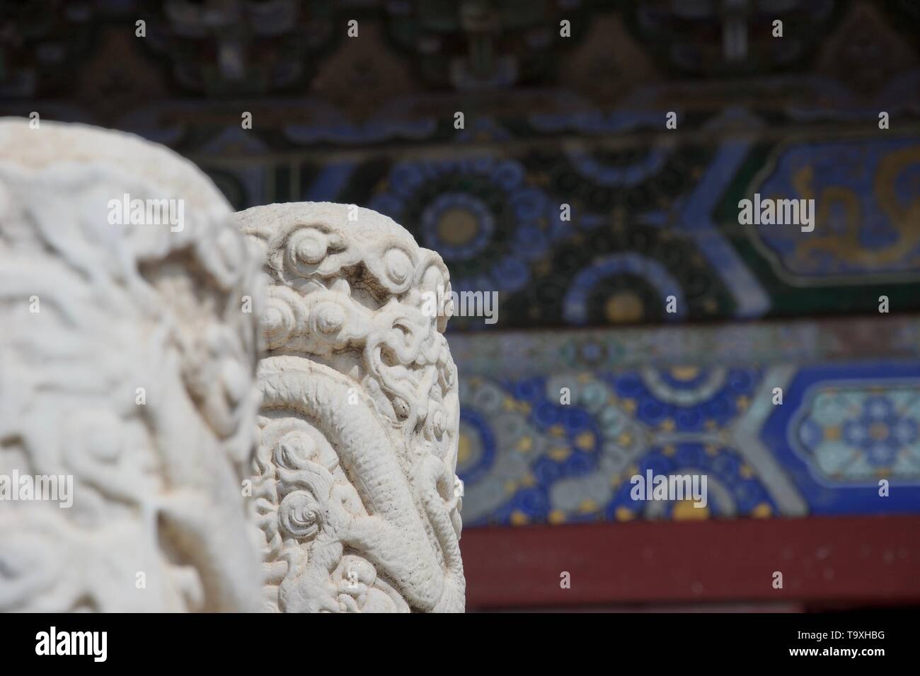 Detail an einer chinesischen Tempel - Aufwändig weißer Marmor Säule im Fokus geschnitzt; Blau komplexe bemalte Wand im Hintergrund Stockfoto