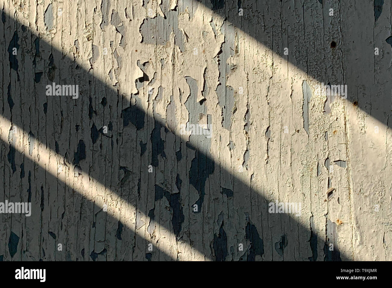 Textur der alte hölzerne Wand mit Rissbildung weißer Farbe mit dunklen Schatten diagonal Stockfoto