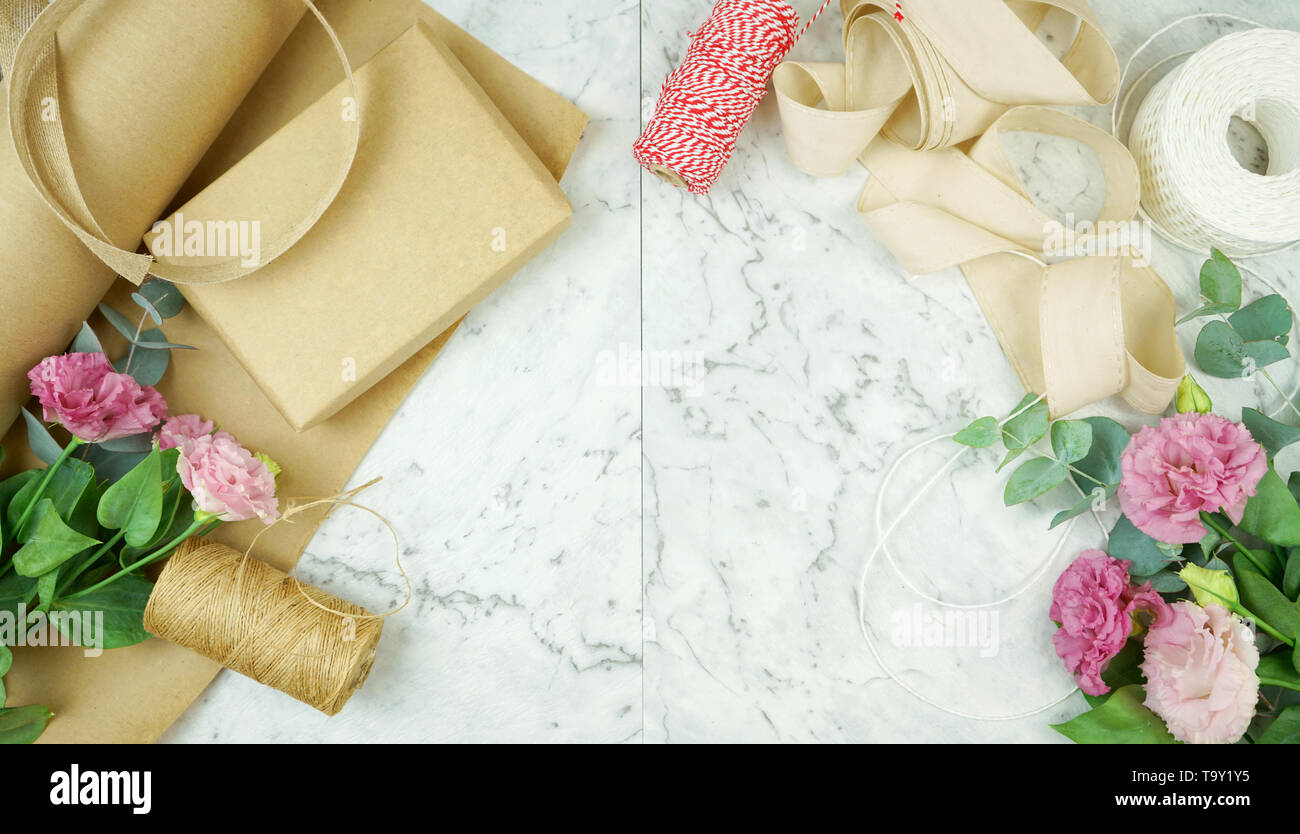 Null - Abfall Geschenkverpackung flatlay Overhead mit Kraftpapier, Jute und Baumwolle Bänder und Garten Blumen für umweltfreundlichen Lebensstil. Stockfoto