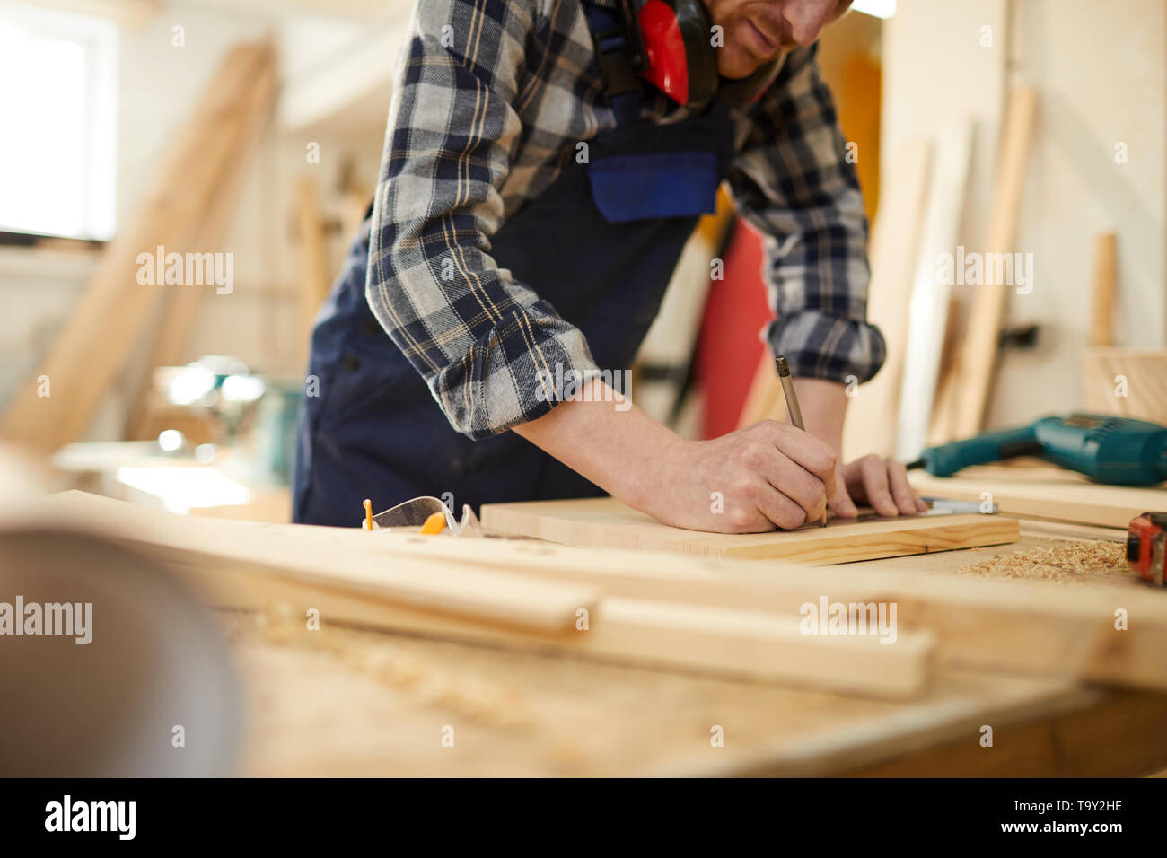 Den mittleren Abschnitt Portrait von Kennzeichnung unkenntlich Tischler Holz während in der Tischlerei arbeiten durch Sonnenlicht beleuchtet, kopieren Raum Stockfoto