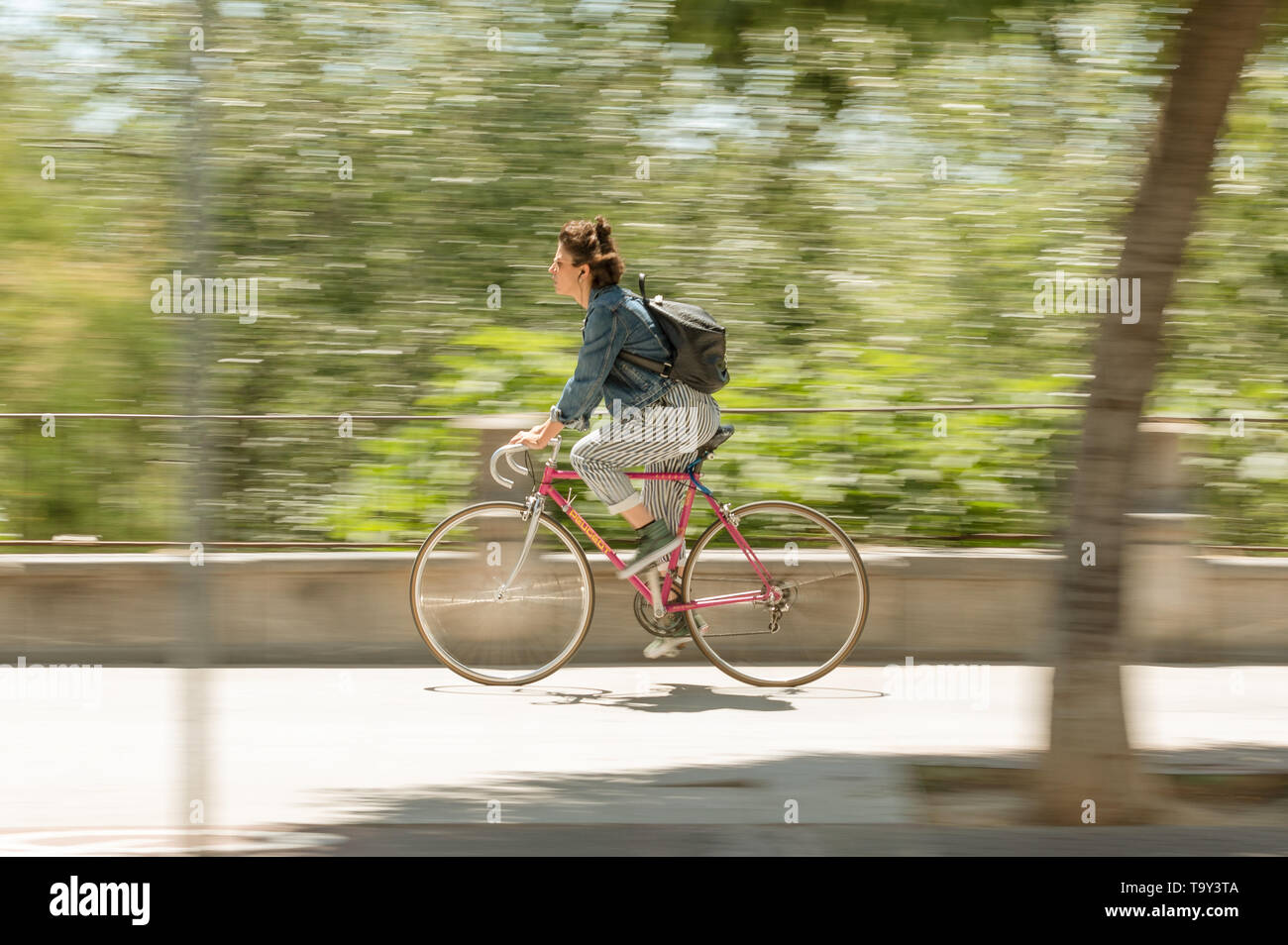 Cordoba, Spanien - 10. Mai 2019: Frau Radfahrer mit gestreiften Hosen Reiten durch die Straße. Stockfoto