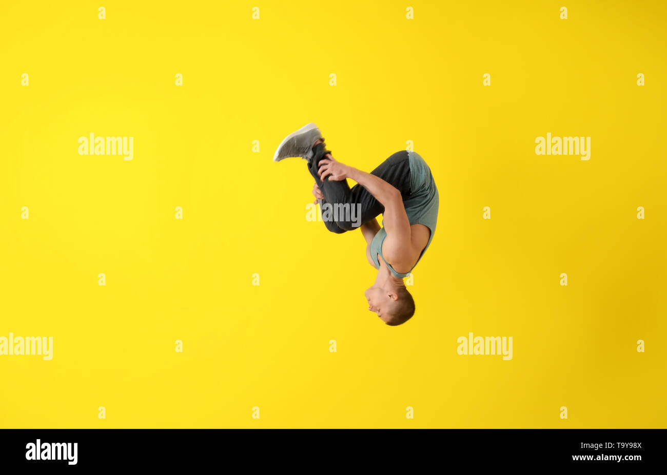 Junge männliche Tänzer tun Flip auf farbigen Hintergrund Stockfoto