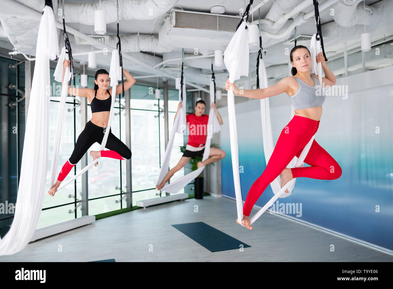 Zwei Frauen und Mann, bequeme Sportkleidung, Flying yoga Stockfoto