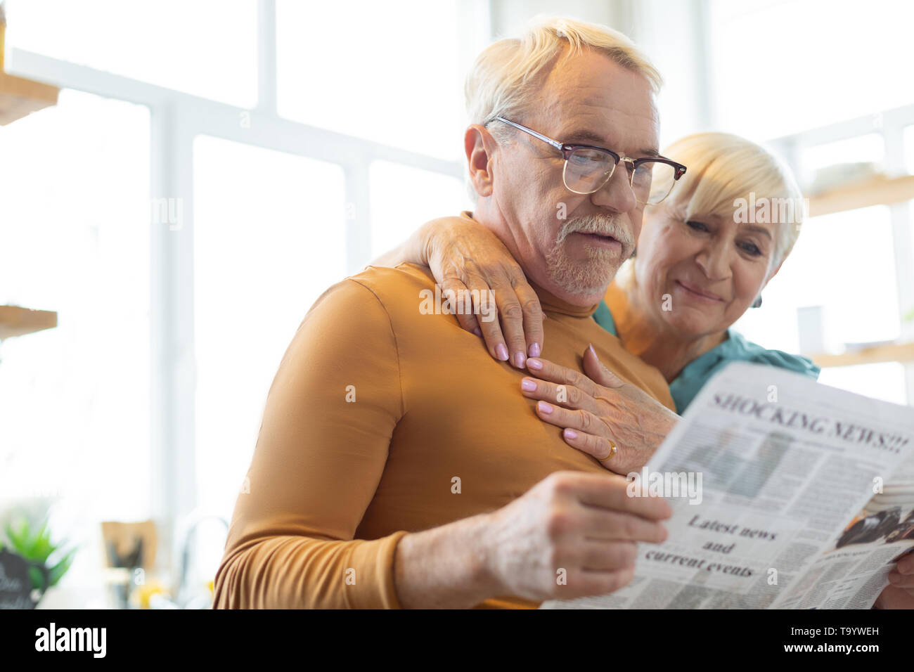 Gesicht Porträt des Ehepartners lesen Papier, während Frau ihn knuddeln Stockfoto