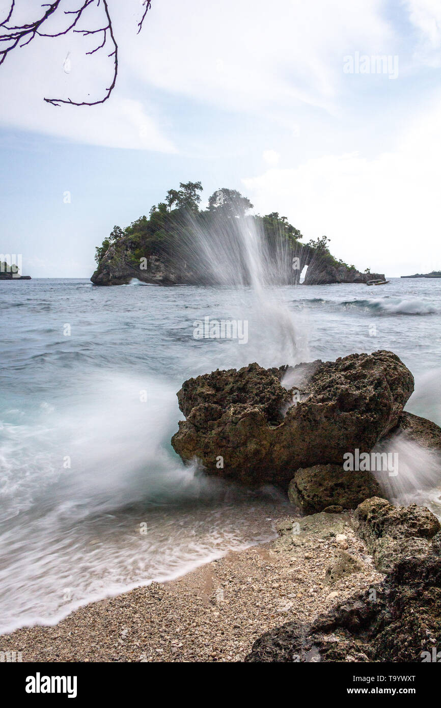 Ausbruch einer Welle, die auf einen Felsen am Strand trifft Stockfoto