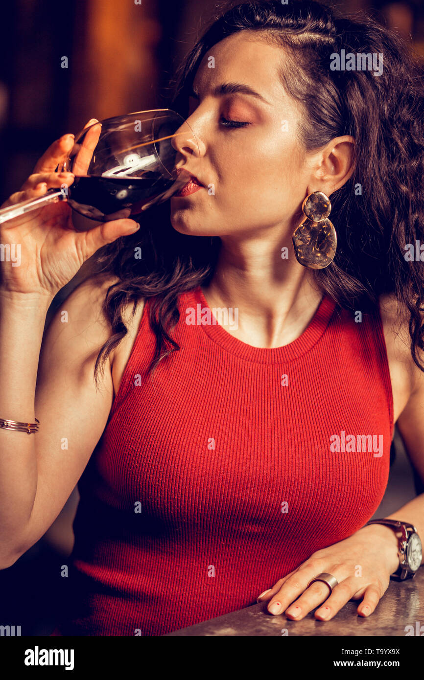 Nahaufnahme von curly Frau in rotem Kleid trinken Rotwein Stockfoto