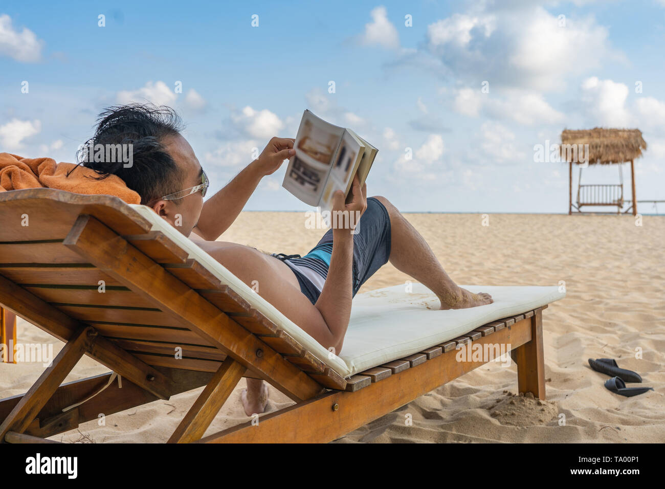 Junger Mann Buch am schönen Strand Stockfoto