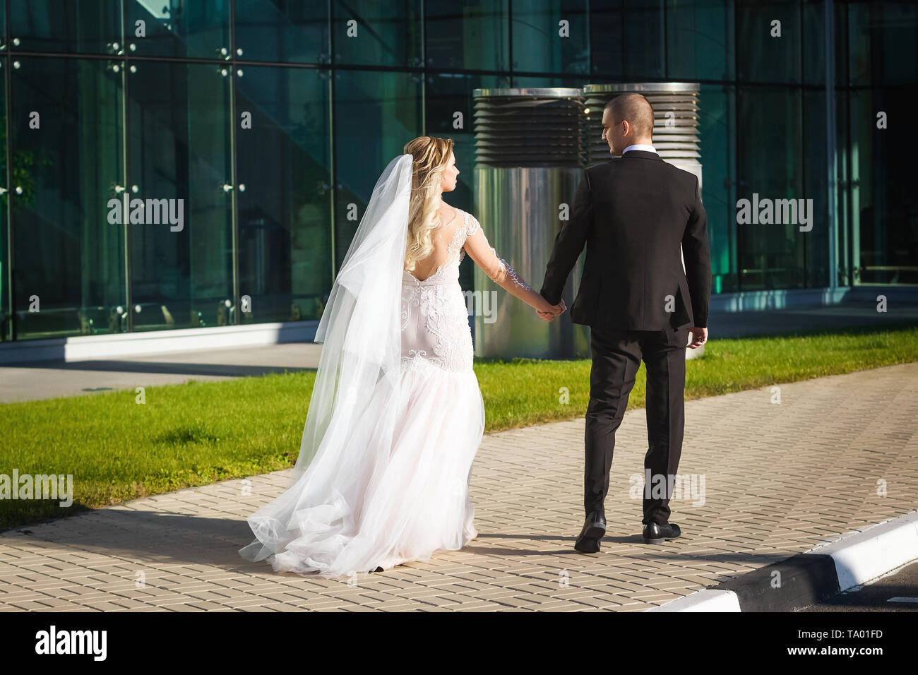 Wunderschöne Braut und Bräutigam Wanderungen in das moderne Gebäude Stockfoto